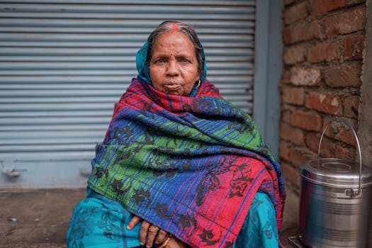 Portrait of an elderly woman in a colorful shawl sitting outdoors in Varanasi, India.