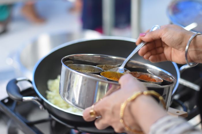 Real photo of an Indian woman cooking with fresh spices