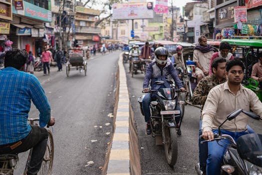 Busy Varanasi street with motorcycles, rickshaws, and pedestrians during the day.