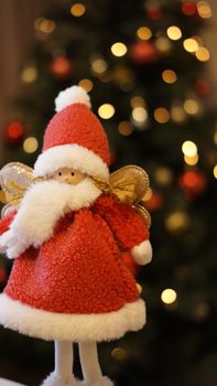 Close-up of a Santa Claus ornament with sparkling Christmas tree in the background.