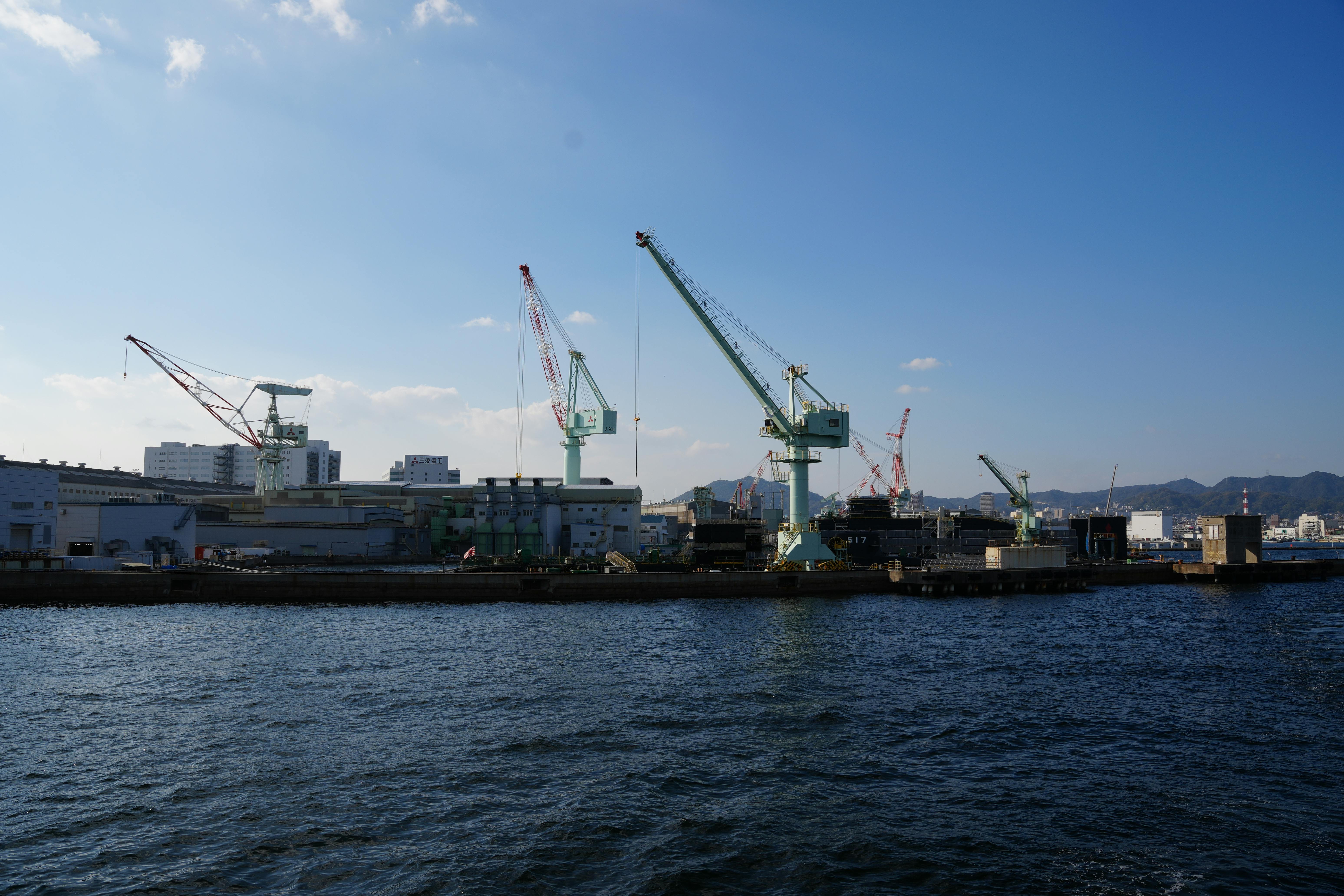 View of cranes at Kobe port under a clear blue sky, showcasing Japan's industrial capabilities.