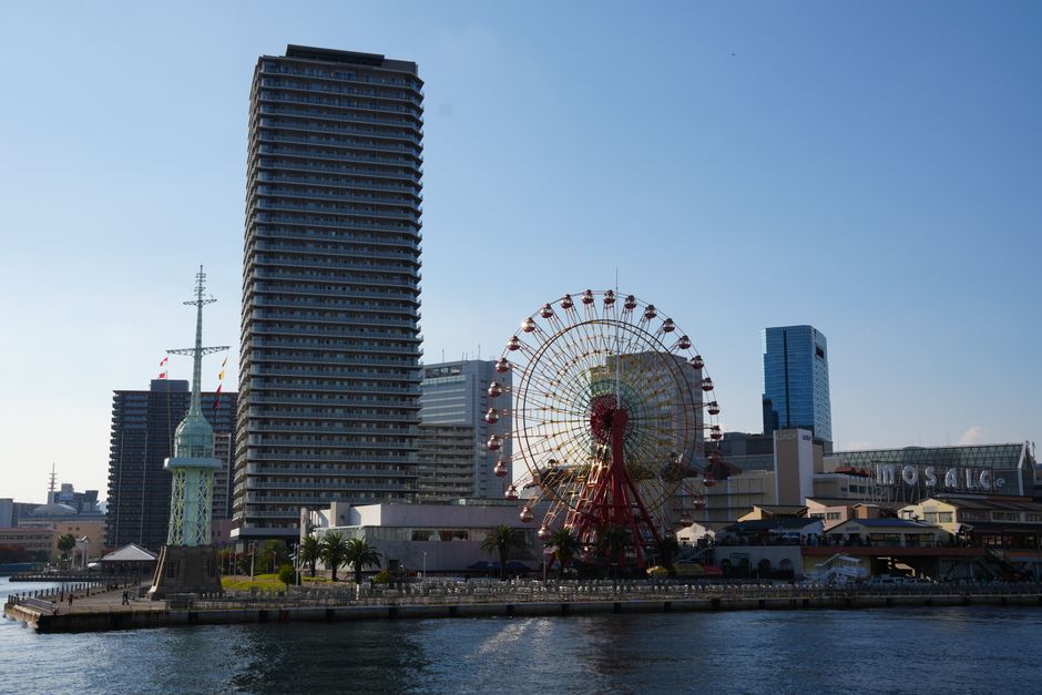 Scenic view of Kobe Harborland, featuring the iconic Port Tower and Ferris Wheel under a clear blue sky.