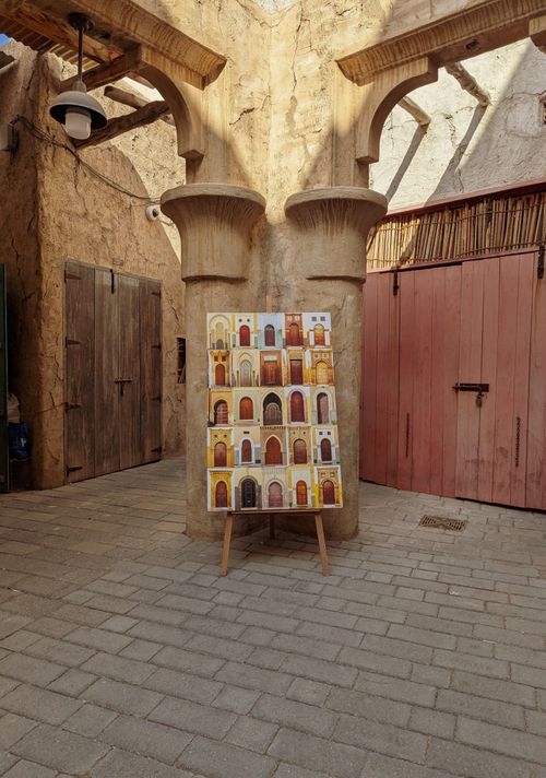 Free Colorful artwork displayed in a rustic courtyard with wooden doors. Stock Photo