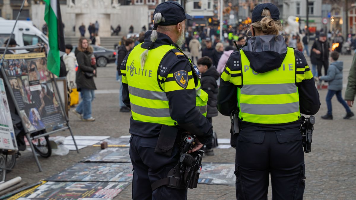 Two Dutch police officers monitor a busy square in Amsterdam, ensuring public safety.