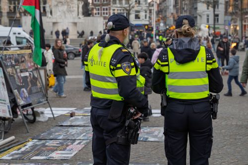 Free Two Dutch police officers monitor a busy square in Amsterdam, ensuring public safety. Stock Photo