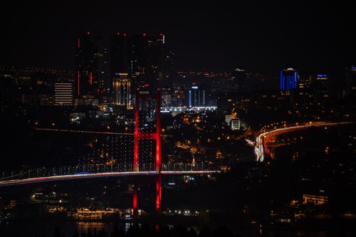 Free Stunning night view of Istanbul with the vibrant Bosphorus Bridge illuminated in red against the city lights. Stock Photo