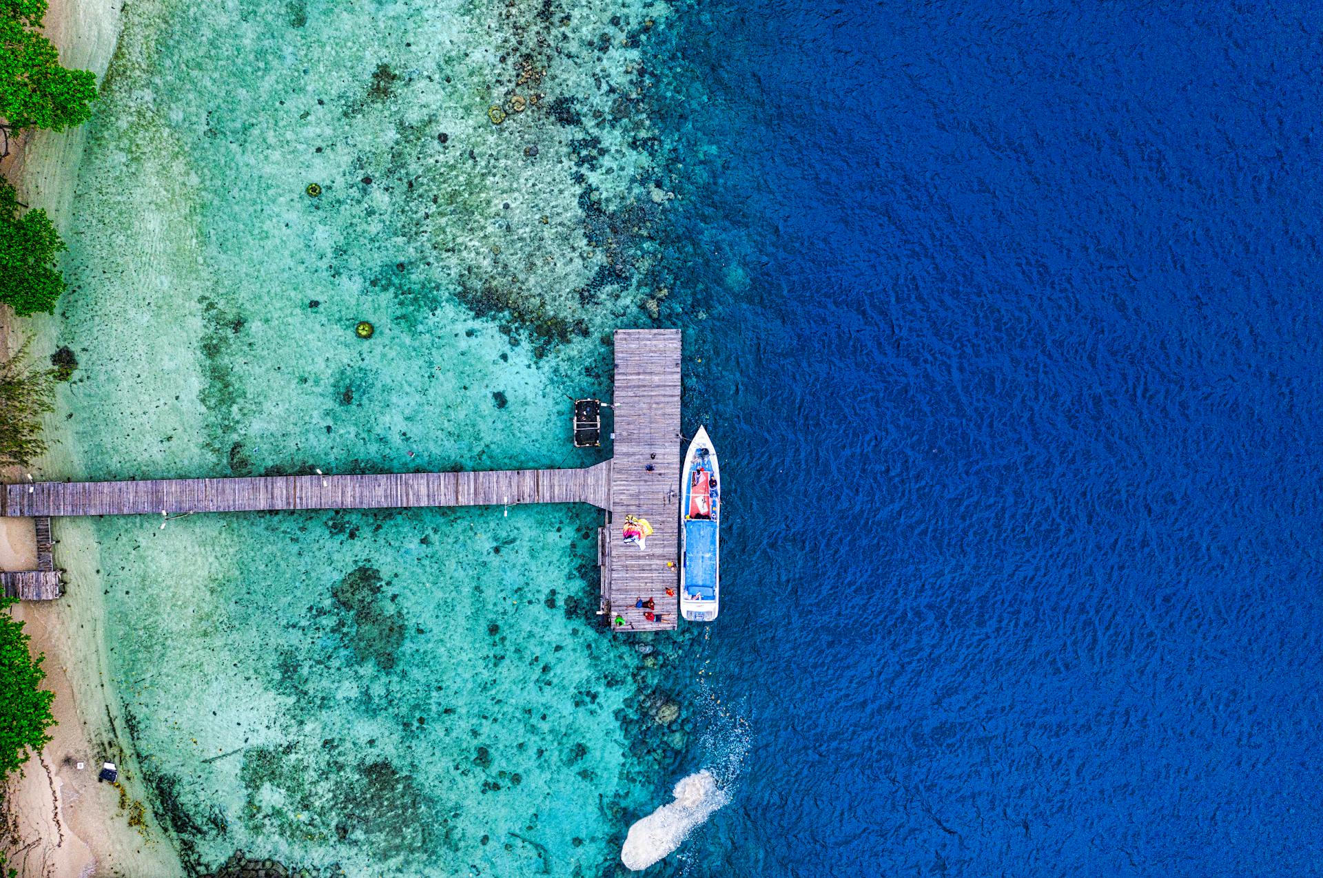 Aerial shot of a boat moored at a dock in vibrant blue waters near Jakarta, Indonesia.
