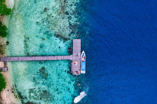 Free Aerial shot of a boat moored at a dock in vibrant blue waters near Jakarta, Indonesia. Stock Photo