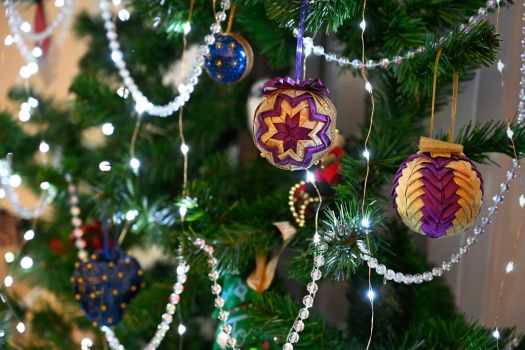 Close-up of a decorated Christmas tree featuring purple ornaments and string lights.