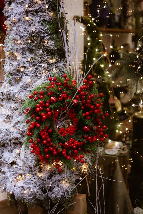 Free A vibrant Christmas wreath on a snowy tree with twinkling lights, creating a festive ambiance. Stock Photo