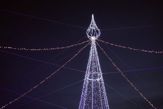 Stunning night view of a festive light-decorated tower with vibrant strings against a dark sky.