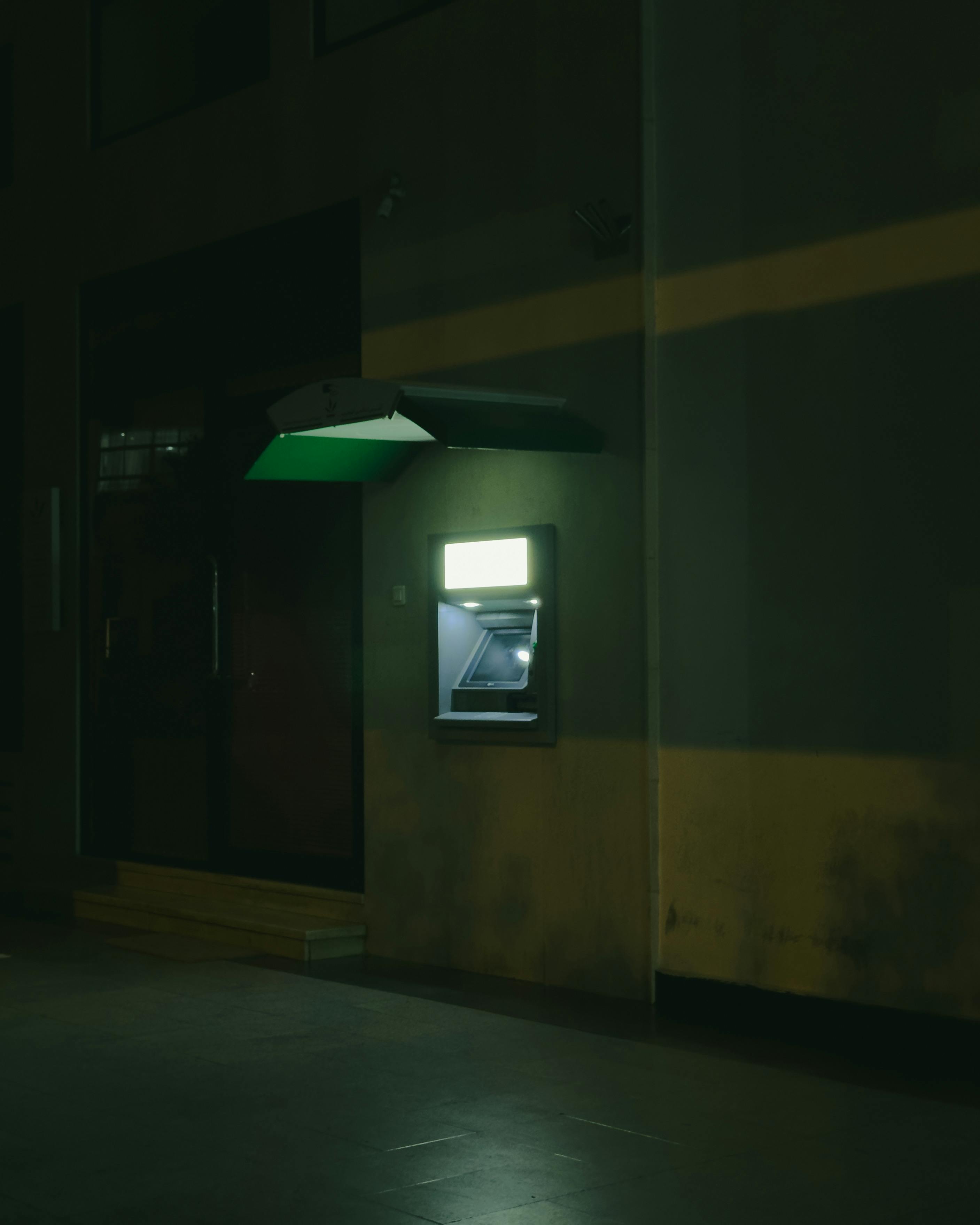 無料 暗い通りにぽつんと建つ ATM は、孤立感と静寂感を与えてくれます。 写真素材