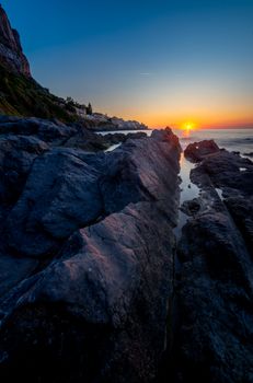Stunning view of the sunset over a rocky coastline with vibrant skies.