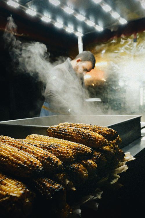 Free Steaming grilled corn from a street vendor at an outdoor night market. Stock Photo