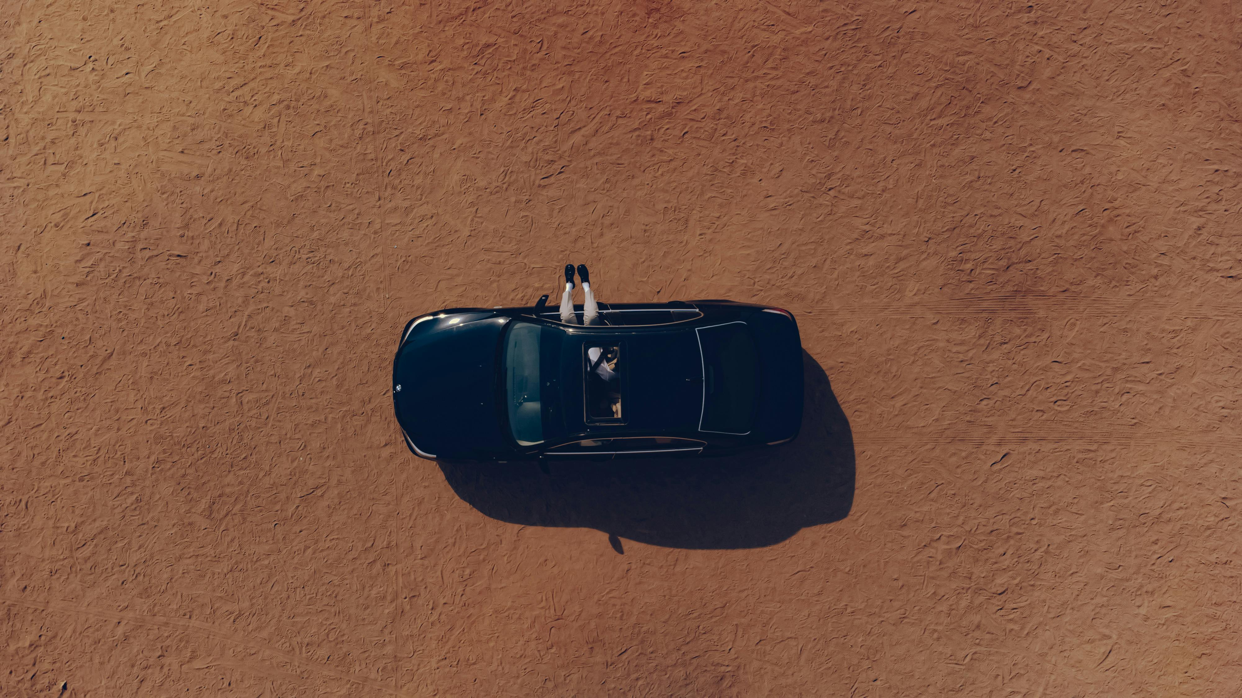 grátis Vista aérea de um carro com as duas rodas visíveis, em uma vasta paisagem desértica. Foto profissional