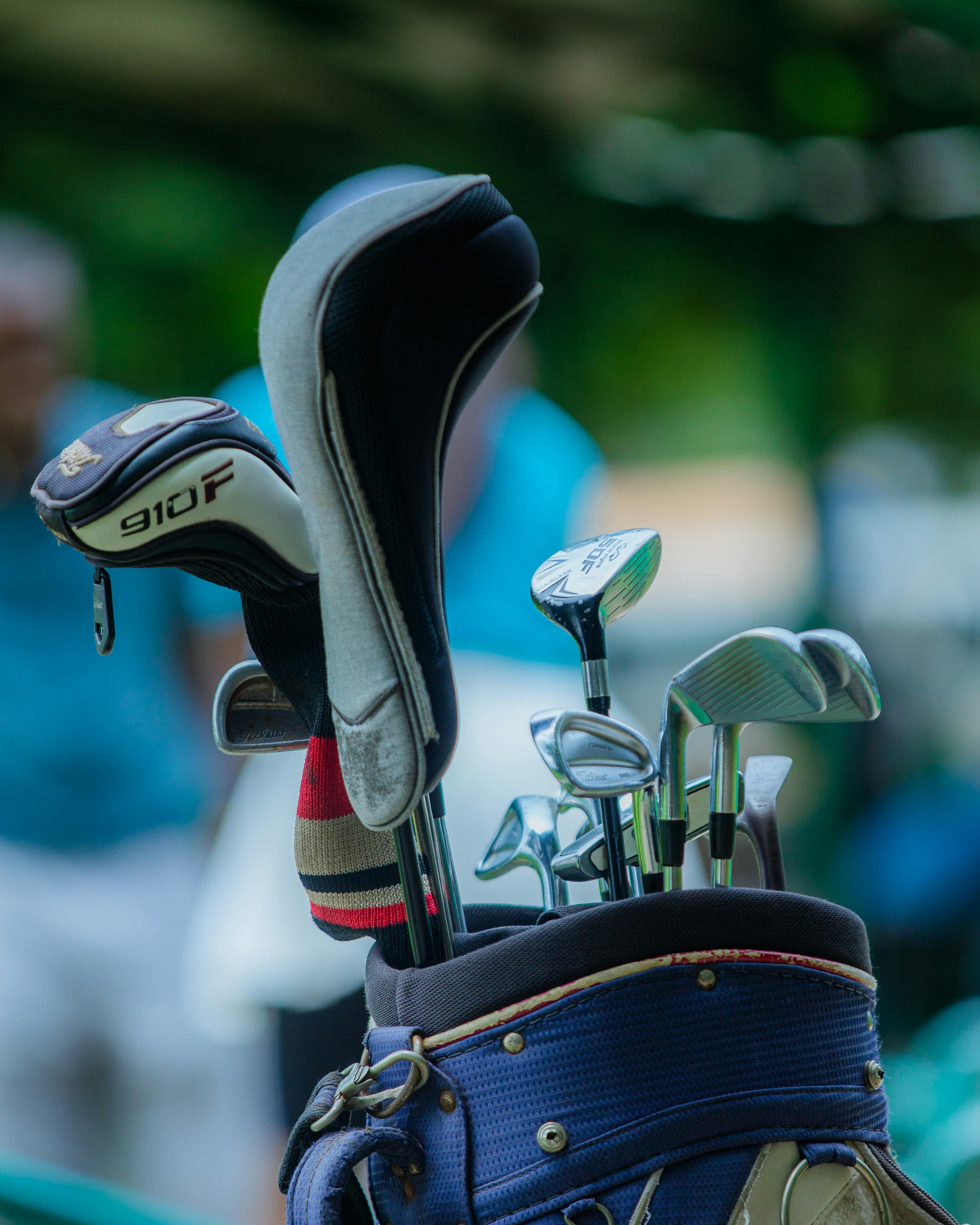 A close-up of golf clubs in a bag on a golf course background, ready for a game.