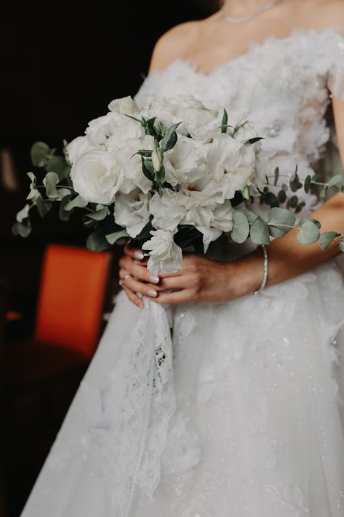 Free Bride in white dress holding a bouquet of white roses and greenery indoors. Stock Photo