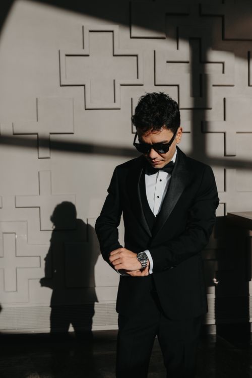 Free A stylish man in a black tuxedo with sunglasses adjusts his cufflinks. Stock Photo