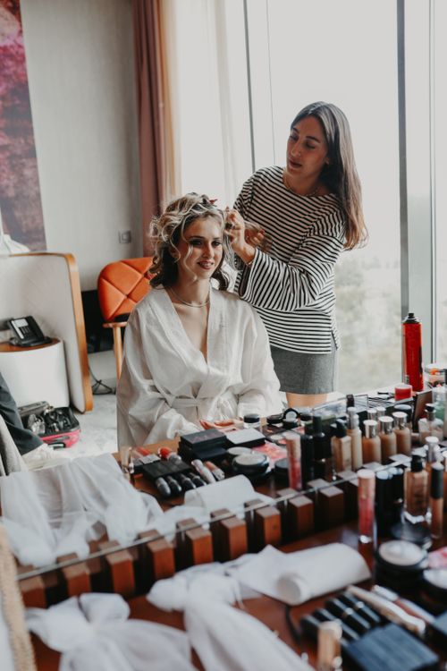 Free A makeup artist styles a woman's hair in a bright room with makeup tools on the table. Stock Photo