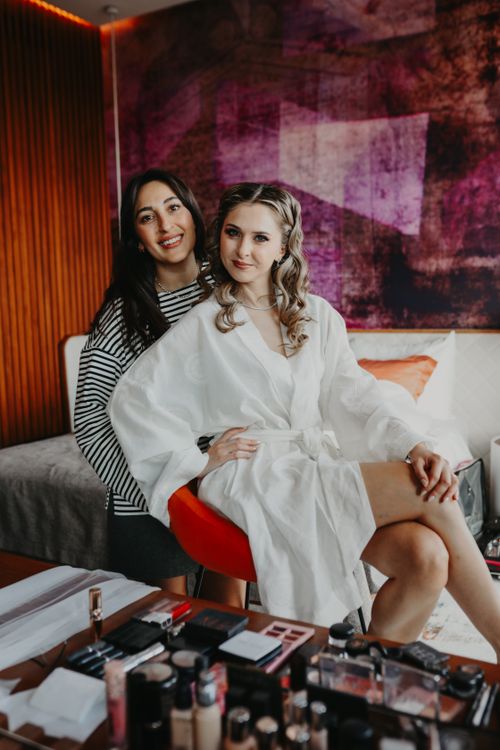 Free Bride and bridesmaid preparing together in a stylish room, surrounded by makeup and beauty products. Stock Photo