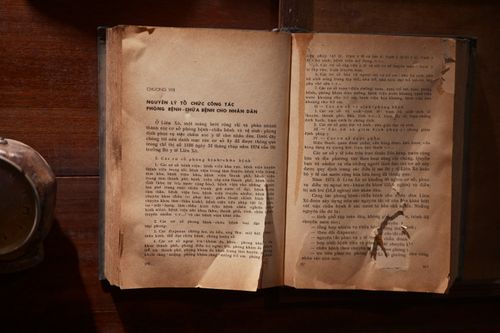 Free A vintage open book with text in Vietnamese on a wooden table, showcasing old literature. Stock Photo