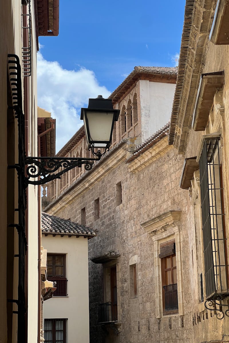 Charming narrow street lined with stone architecture and vintage lamp post under clear blue sky.