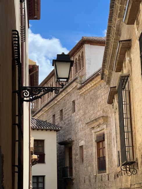 Charming narrow street lined with stone architecture and vintage lamp post under clear blue sky.