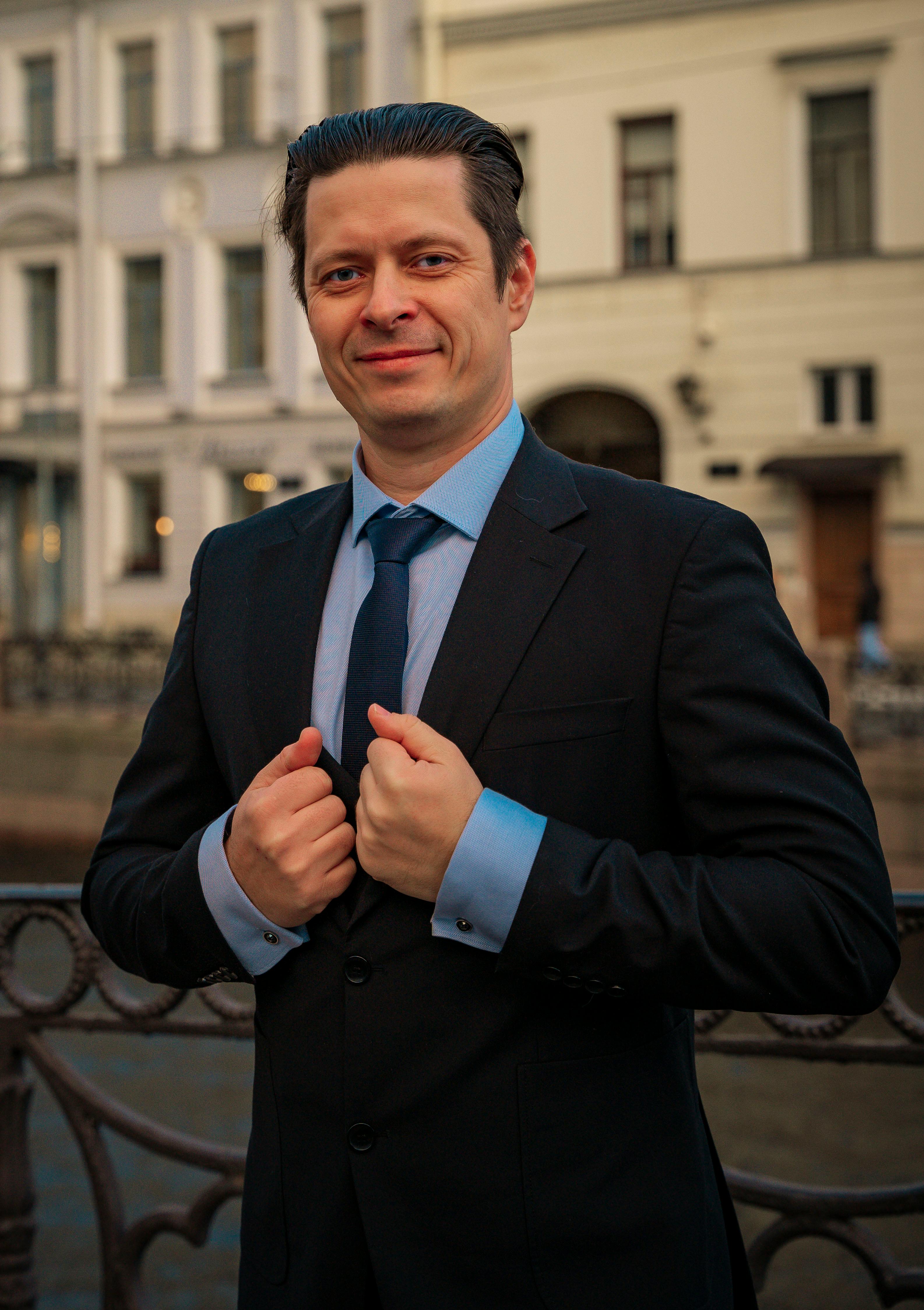 Smiling businessman in suit poses confidently against urban background.