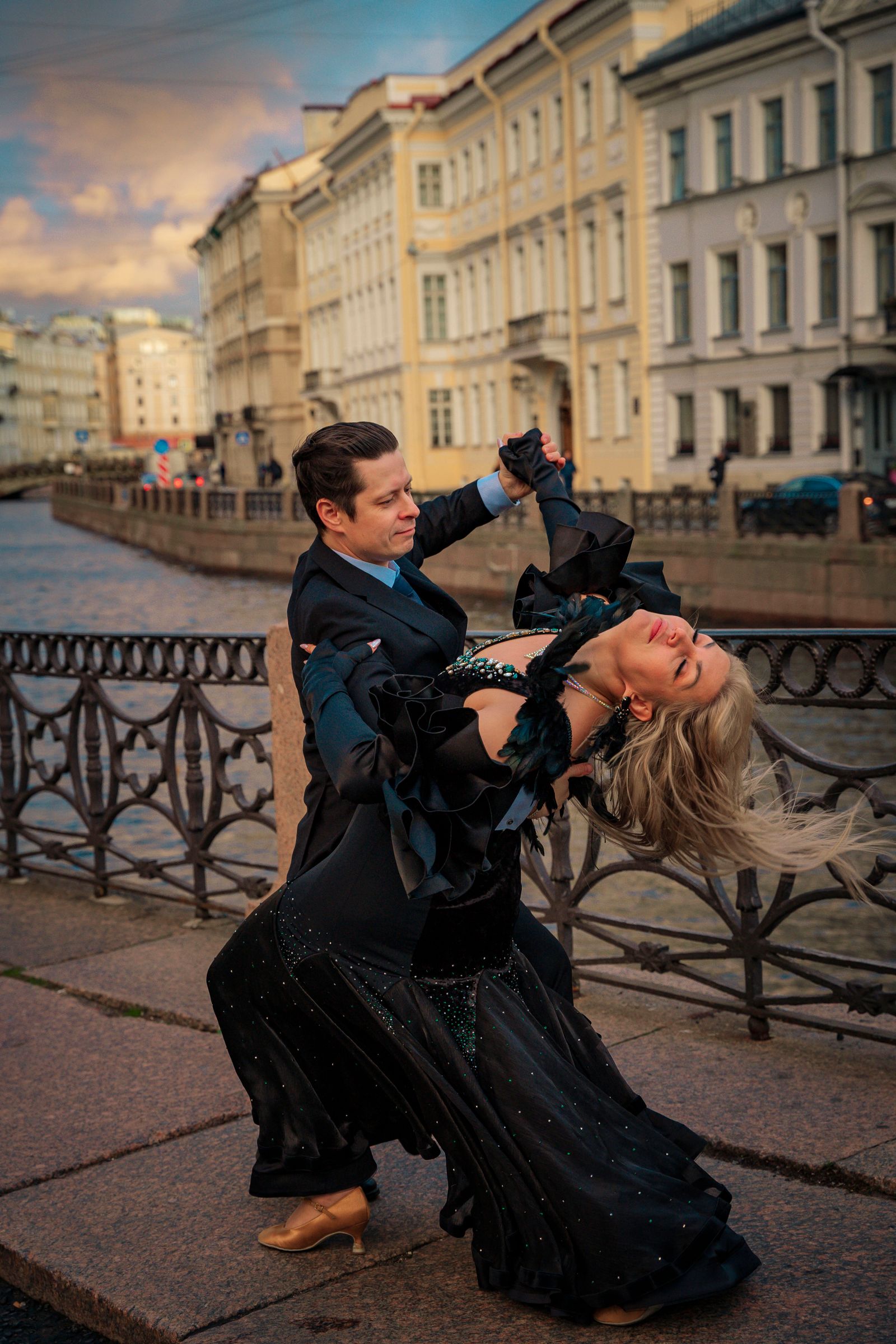 Smooth (American Smooth) — elegant couple in a dramatic dip by a canal at dusk. Stock photo.