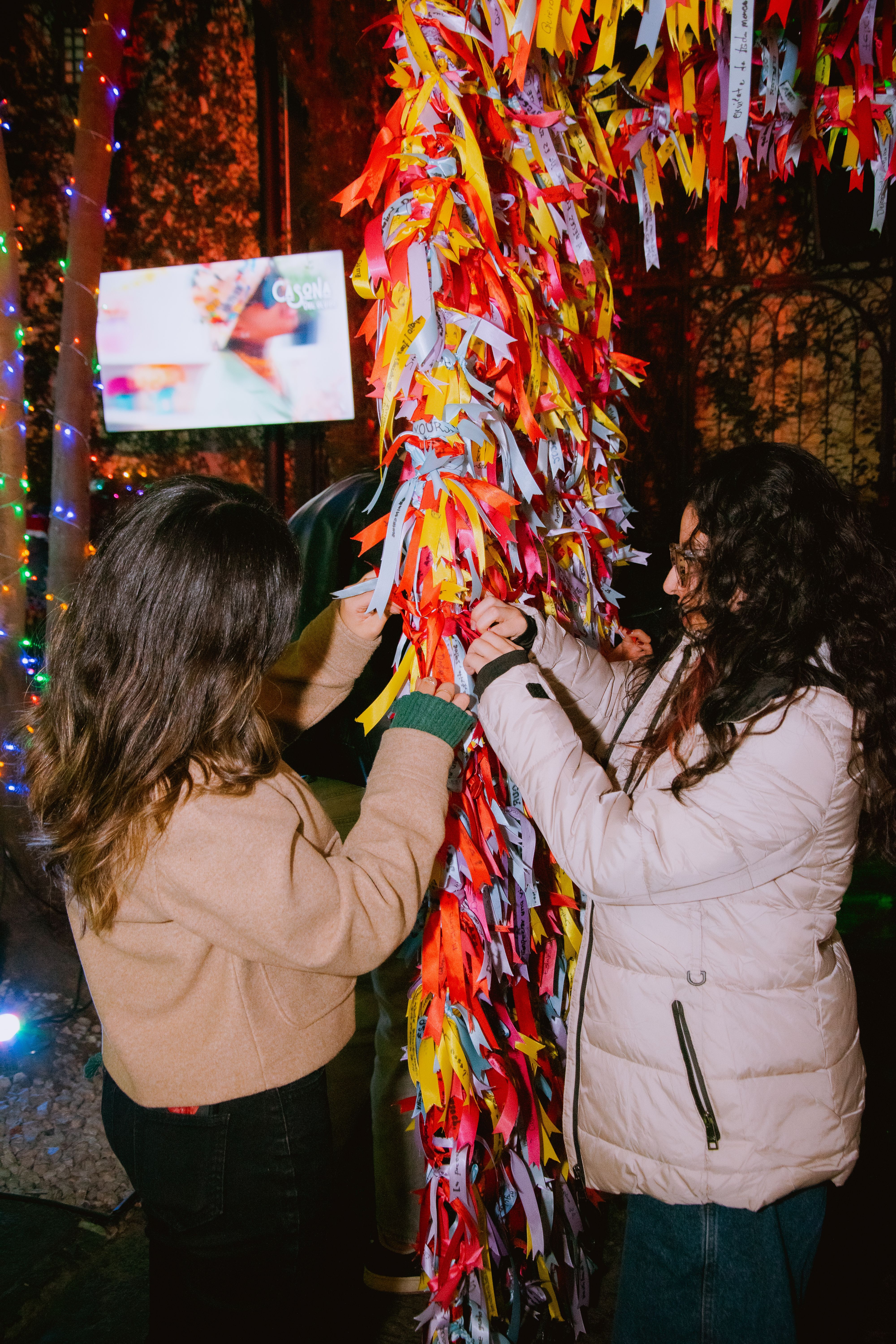 Two Women Attaching Colorful Ribbons in Night Festival · Free Stock Photo