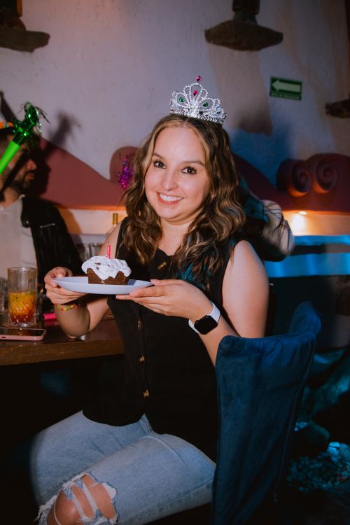 Free Smiling woman wearing a tiara celebrates her birthday indoors with cake and friends. Stock Photo