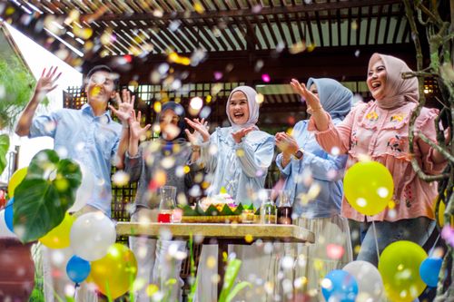 Free A lively group of friends celebrating outdoors with balloons and confetti, symbolizing joy and togetherness. Stock Photo