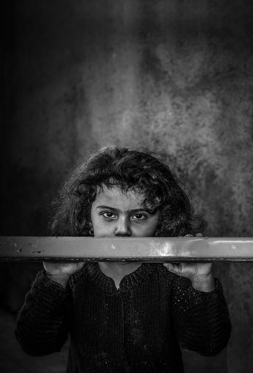 Free Black and white portrait of a young girl looking solemnly, holding a metal bar. Stock Photo