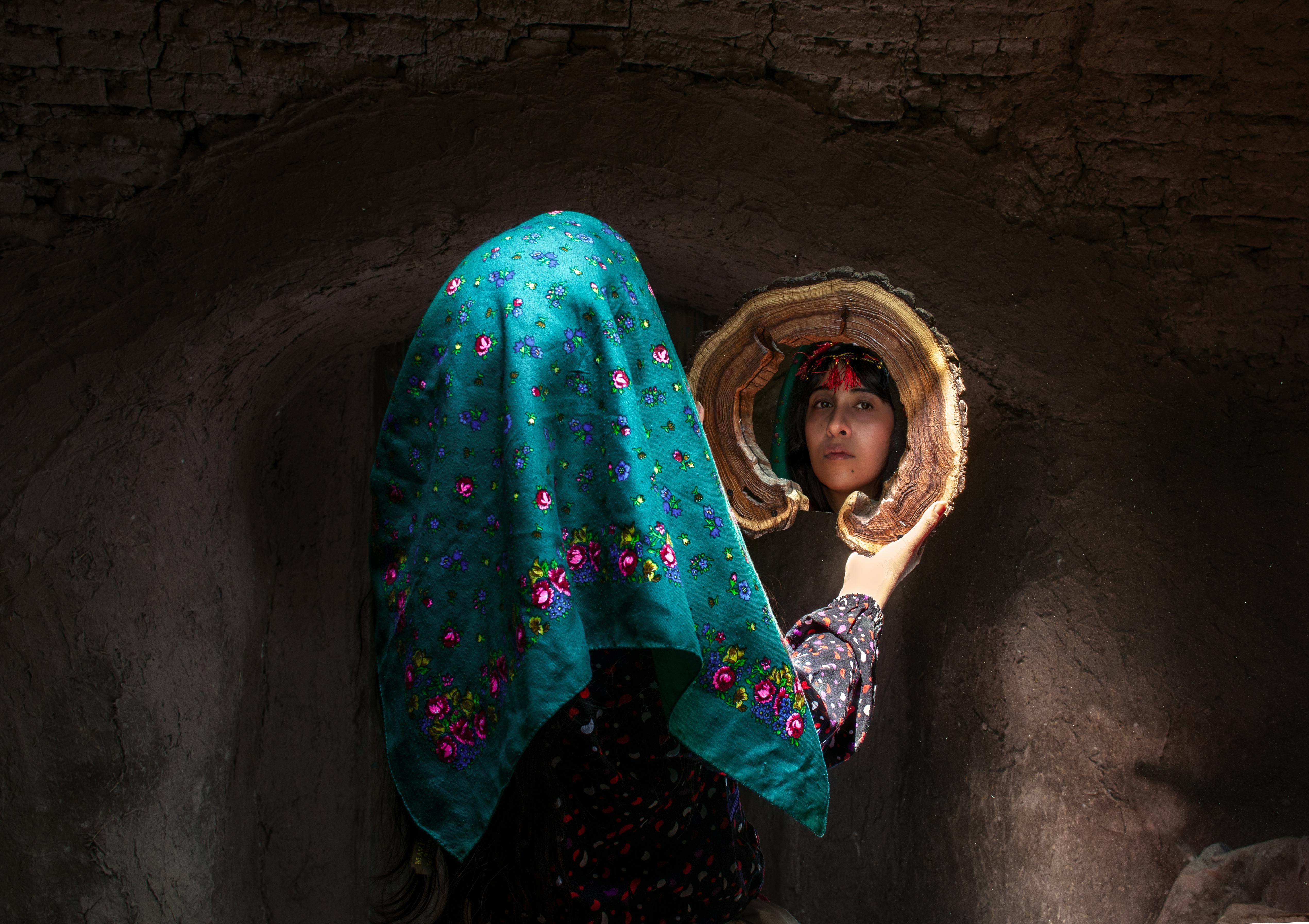 Artistic portrait of a woman with a mirror in a traditional setting in Iran.