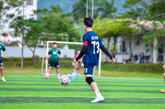Adult soccer players in action on a sunlit field in Hanoi, showcasing skills and teamwork.