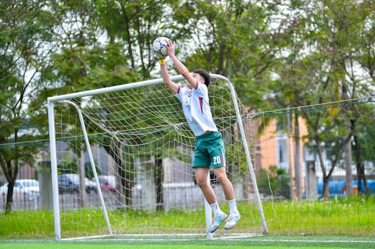 A soccer goalkeeper makes a dynamic save outdoors in Hà Nội, Việt Nam.