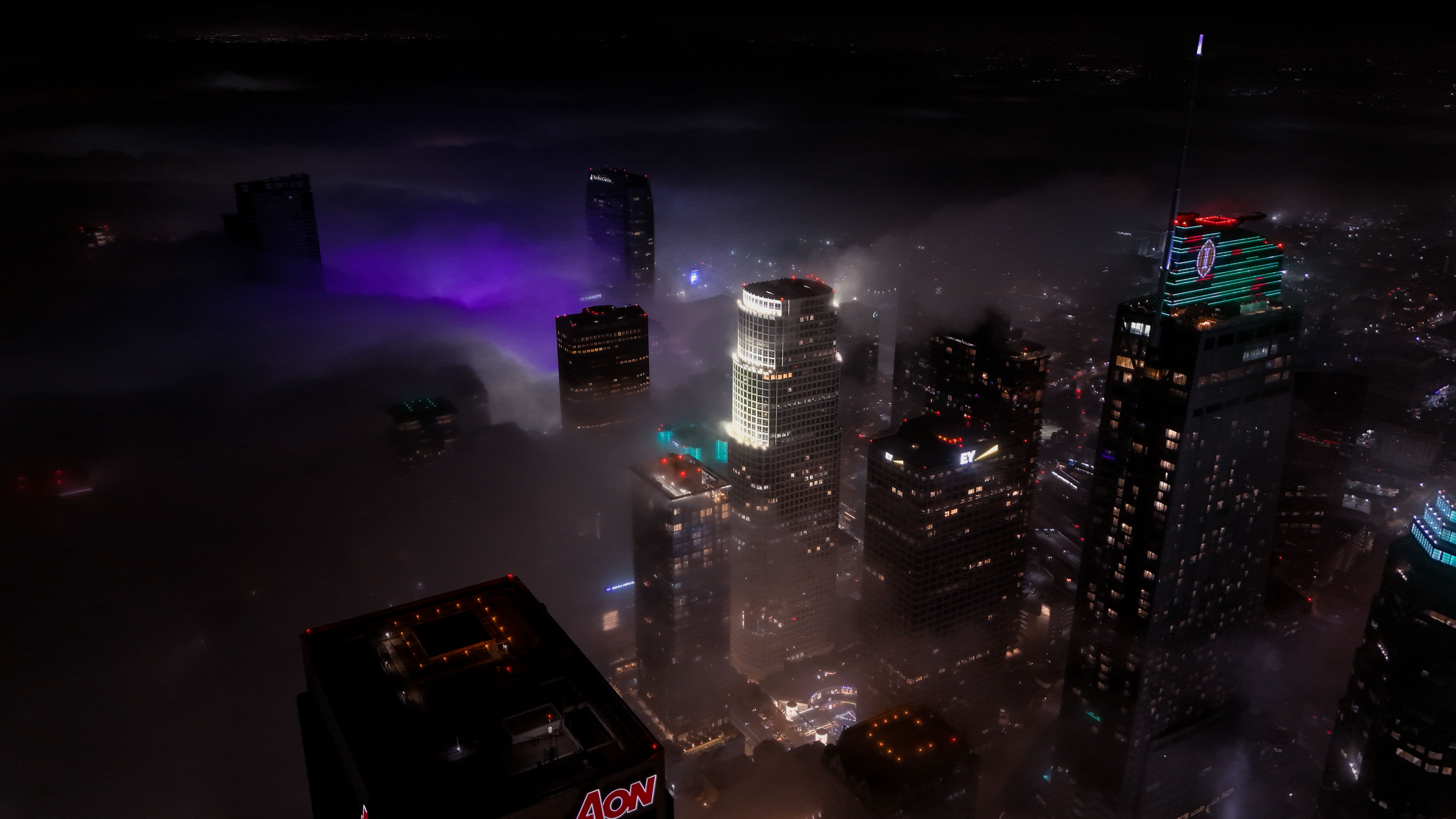 Spectacular Los Angeles Hollywood Sign & City Tour by Helicopter Review 2026 - A stunning aerial view of skyscrapers enveloped in fog and city lights at night.