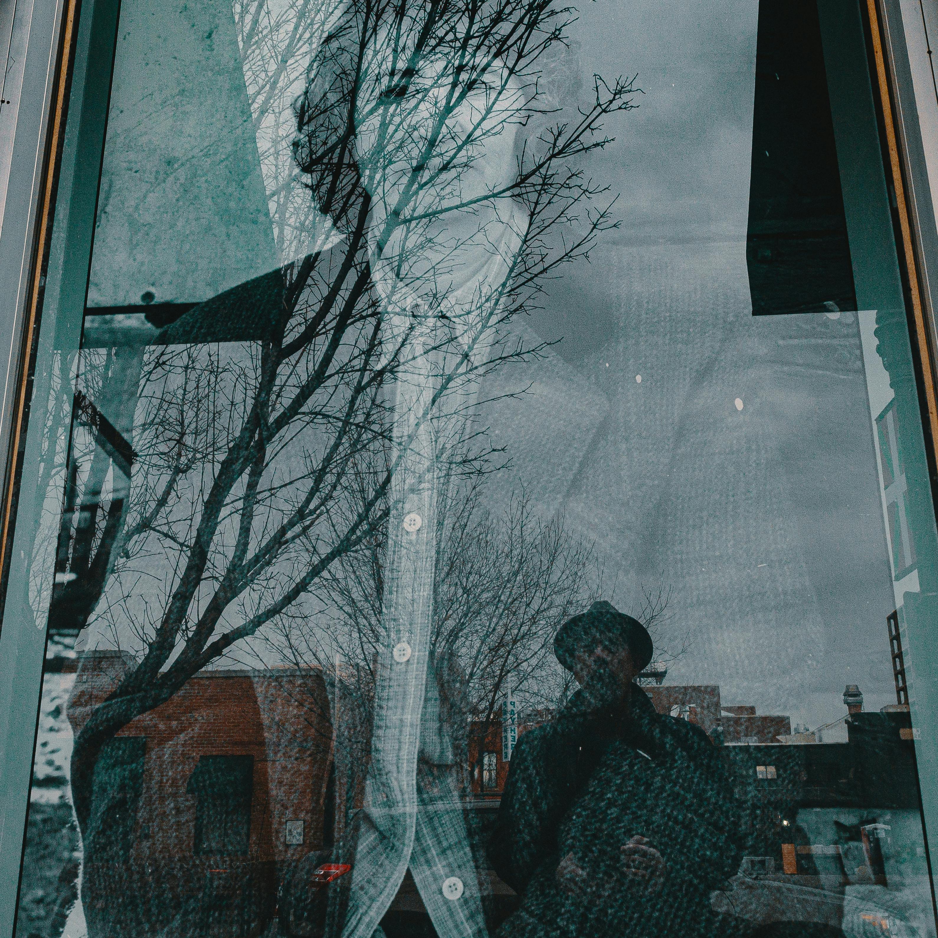 复古城市的窗户中映出一个男人的倒影，背景是树木和建筑