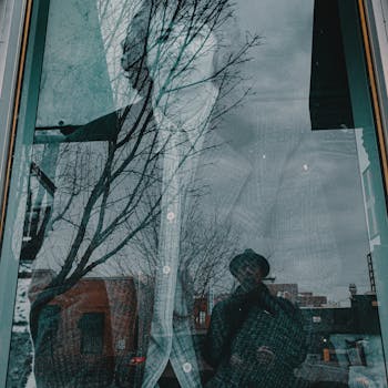 复古城市的窗户中映出一个男人的倒影，背景是树木和建筑
