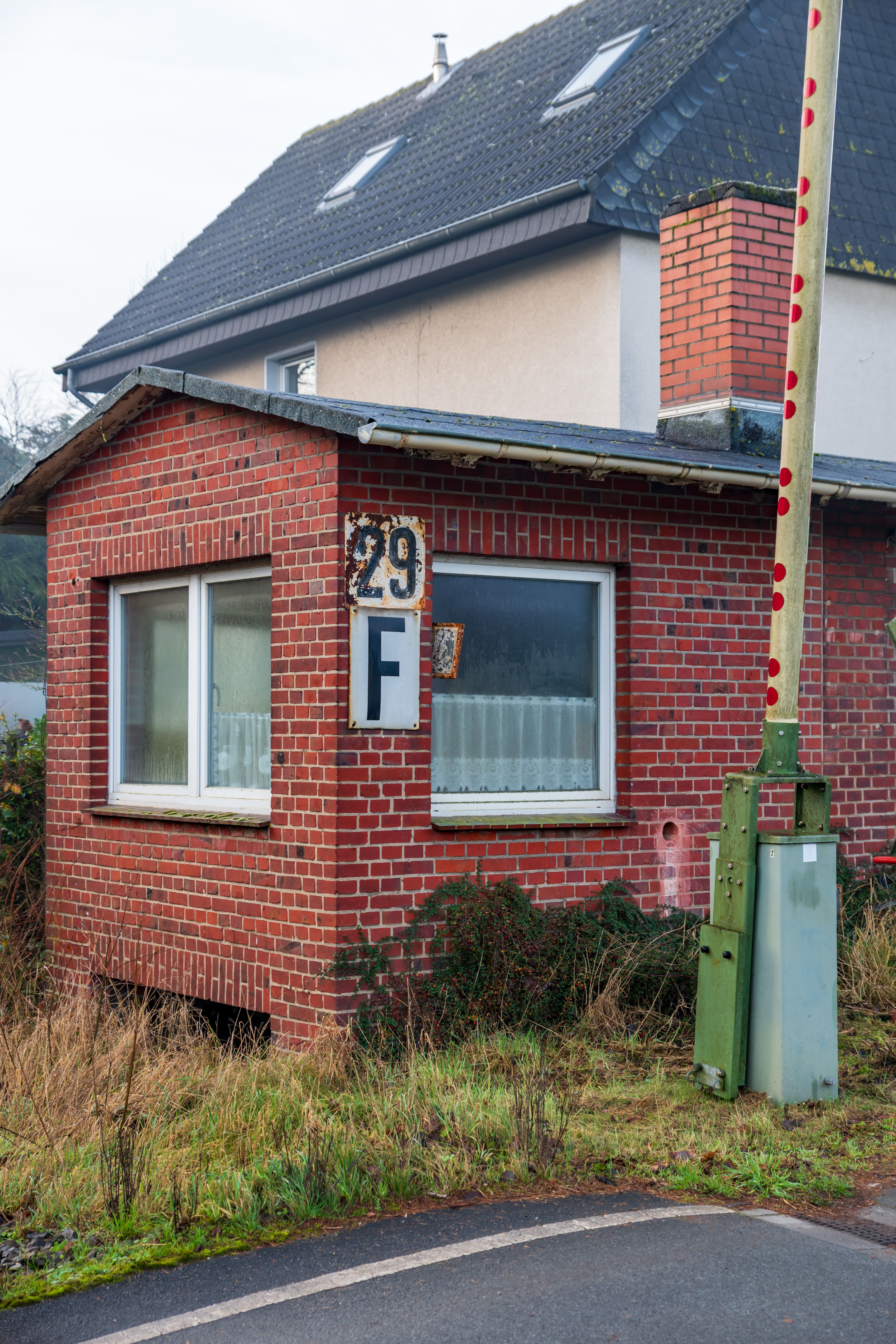 Charming red brick house in a suburban area with a visible number 29 sign, surrounded by grass.