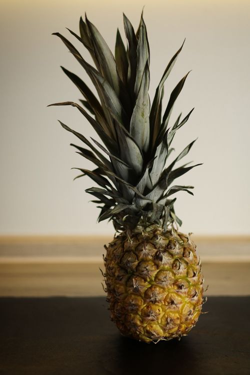 Free A ripe pineapple with a detailed texture placed indoors on a wooden surface. Stock Photo