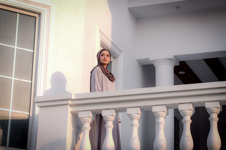 Woman in hijab on a sunlit balcony, showcasing modest fashion style