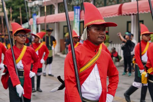 Free Participants in traditional red costumes parade through Yogyakarta, celebrating Indonesian cultural heritage. Stock Photo