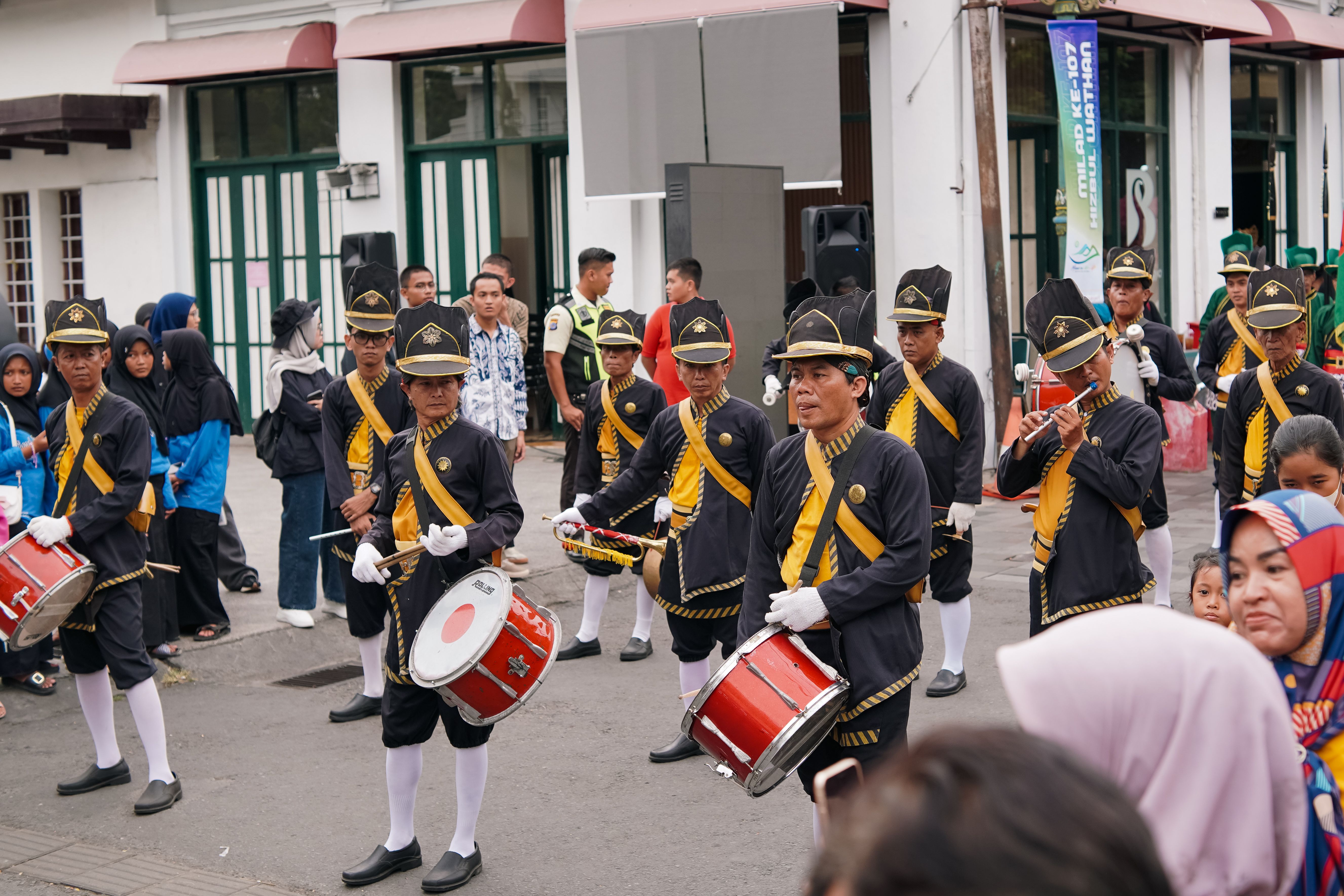 A vibrant street parade in Yogyakarta featuring traditional drum performers in ceremonial costumes.