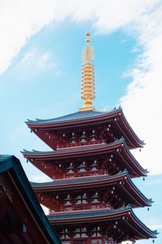 A traditional Japanese pagoda reaches into a bright blue sky, showcasing intricate architectural details.
