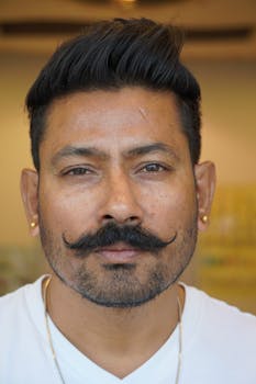 Detailed portrait of an adult man with styled mustache and earrings.
