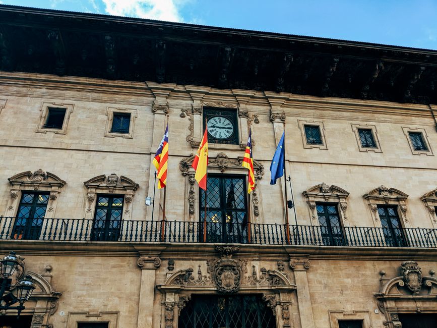 Fachada del Ayuntamiento de Palma con banderas y arquitectura histórica.