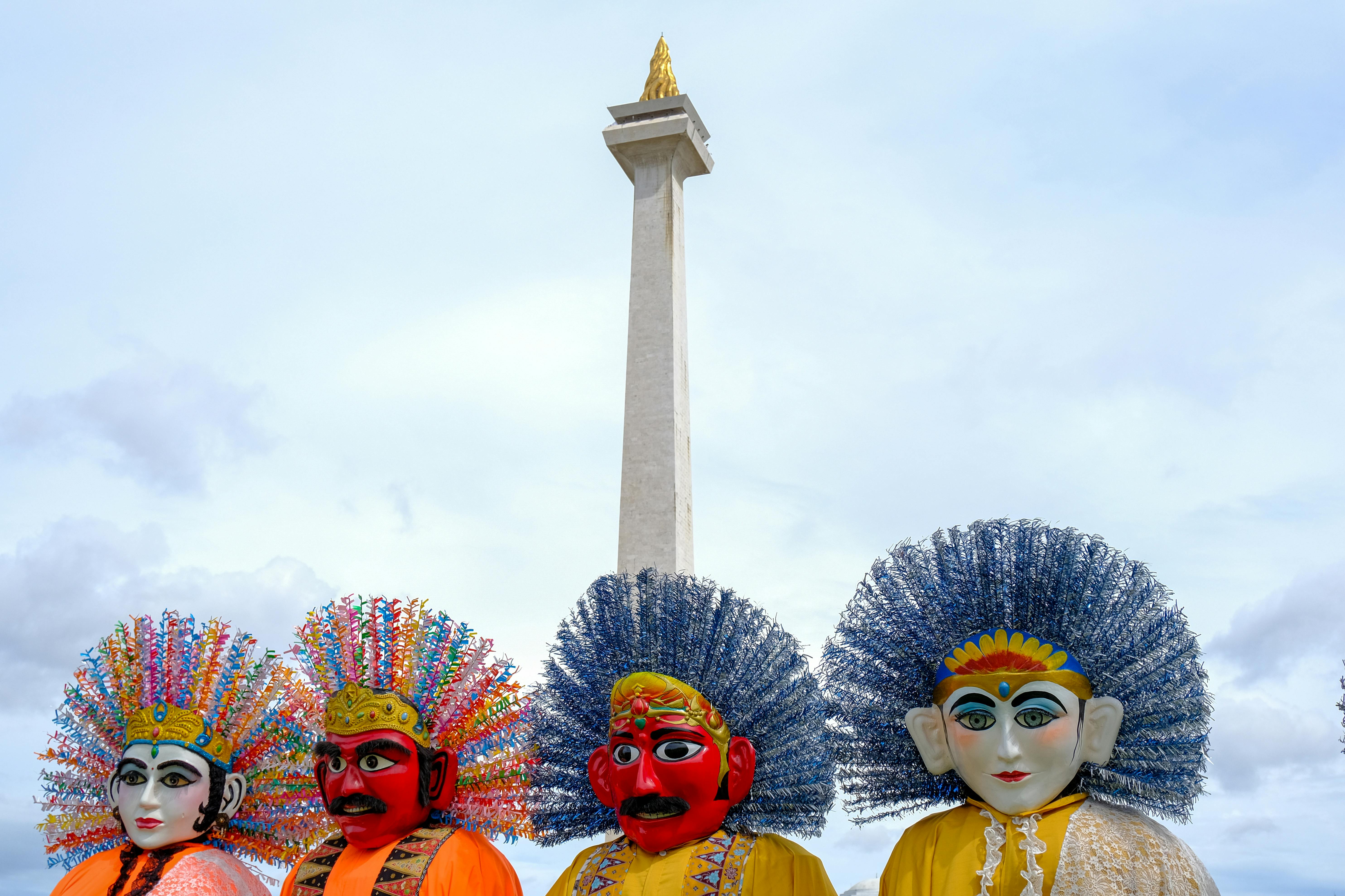 Ondel-ondel figures stand before Jakarta's iconic Monas, showcasing vibrant Indonesian culture. - Yakarta