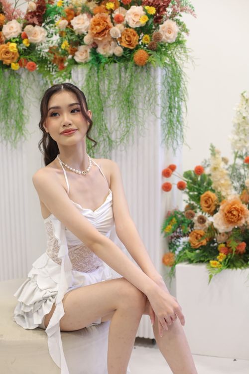 Free Young woman in a white dress posed elegantly with floral arrangements. Stock Photo