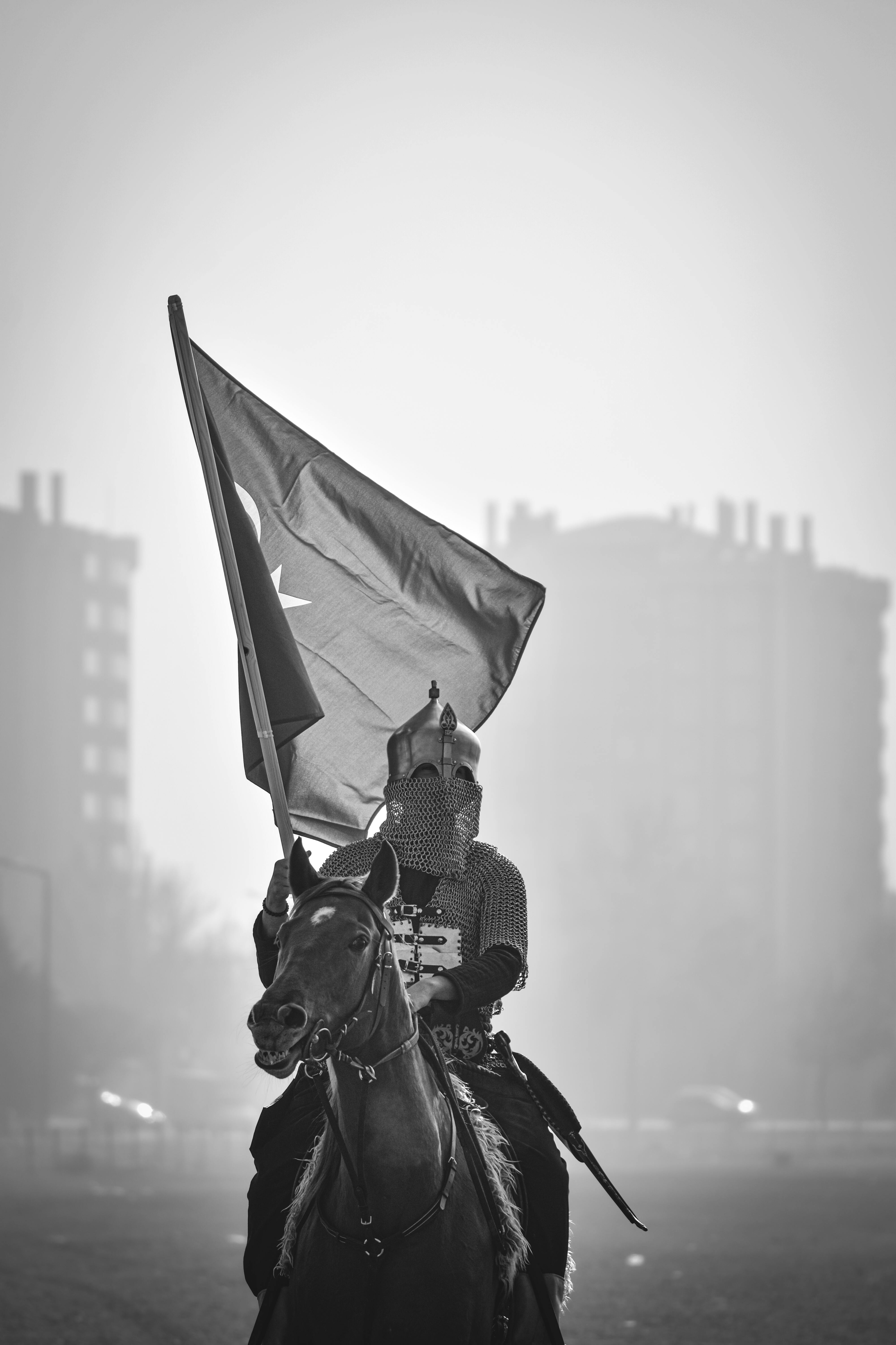 Dramatic black and white image of a historic cavalry rider holding a Turkish flag in Konya, Türkiye.